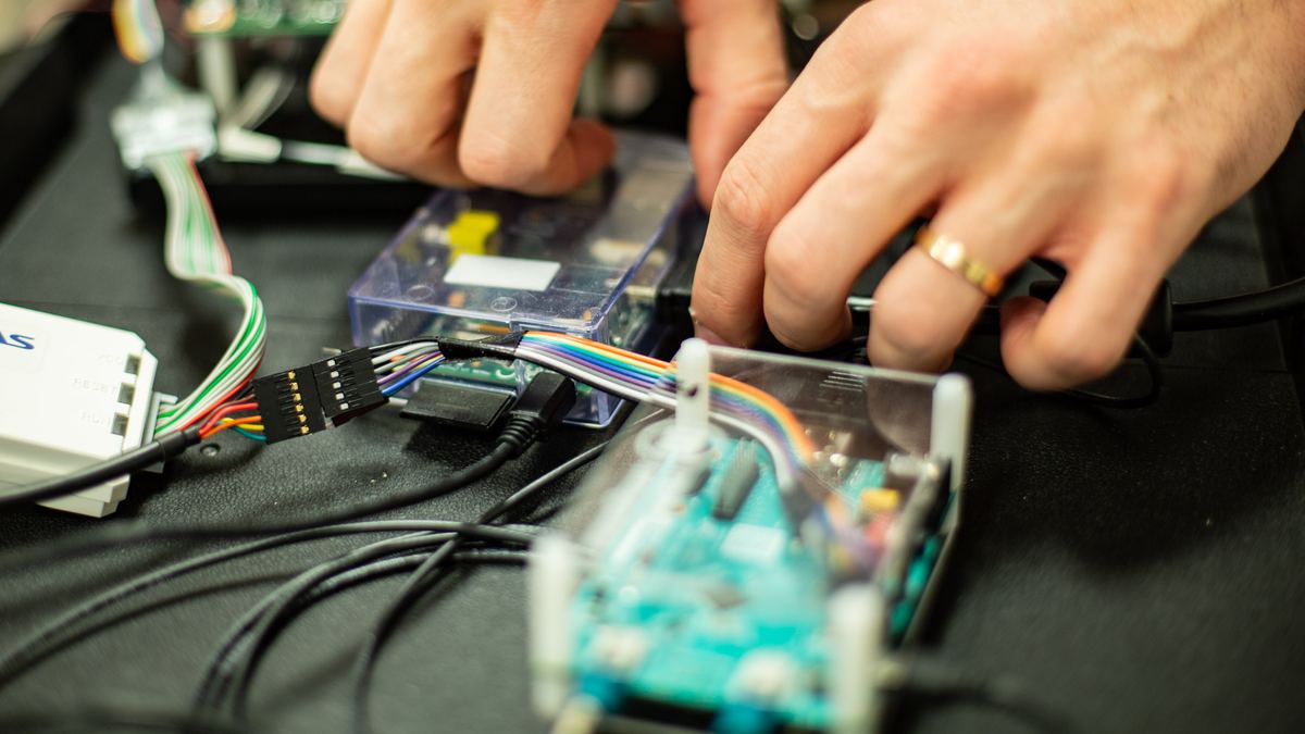 Engineer connecting a ribbon-cable harness to an electronic control unit on a diagnostics bench