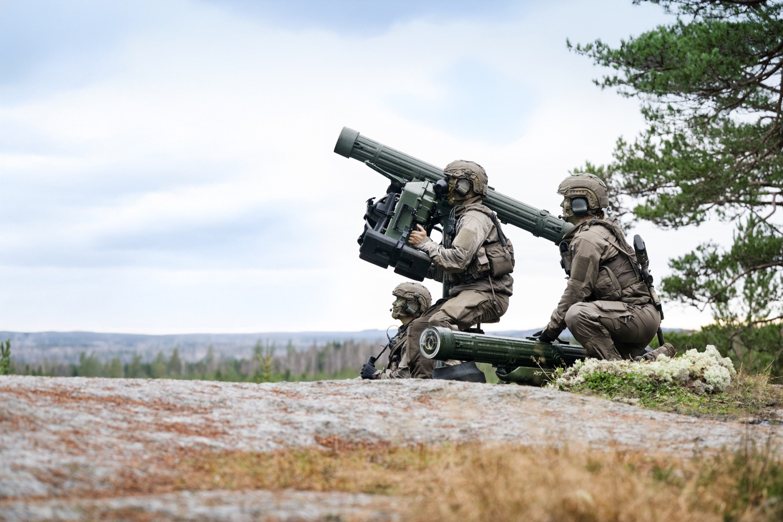 An RBS 70 NG firing unit on a rocky ridge, one gunner at the sight and two crew alongside